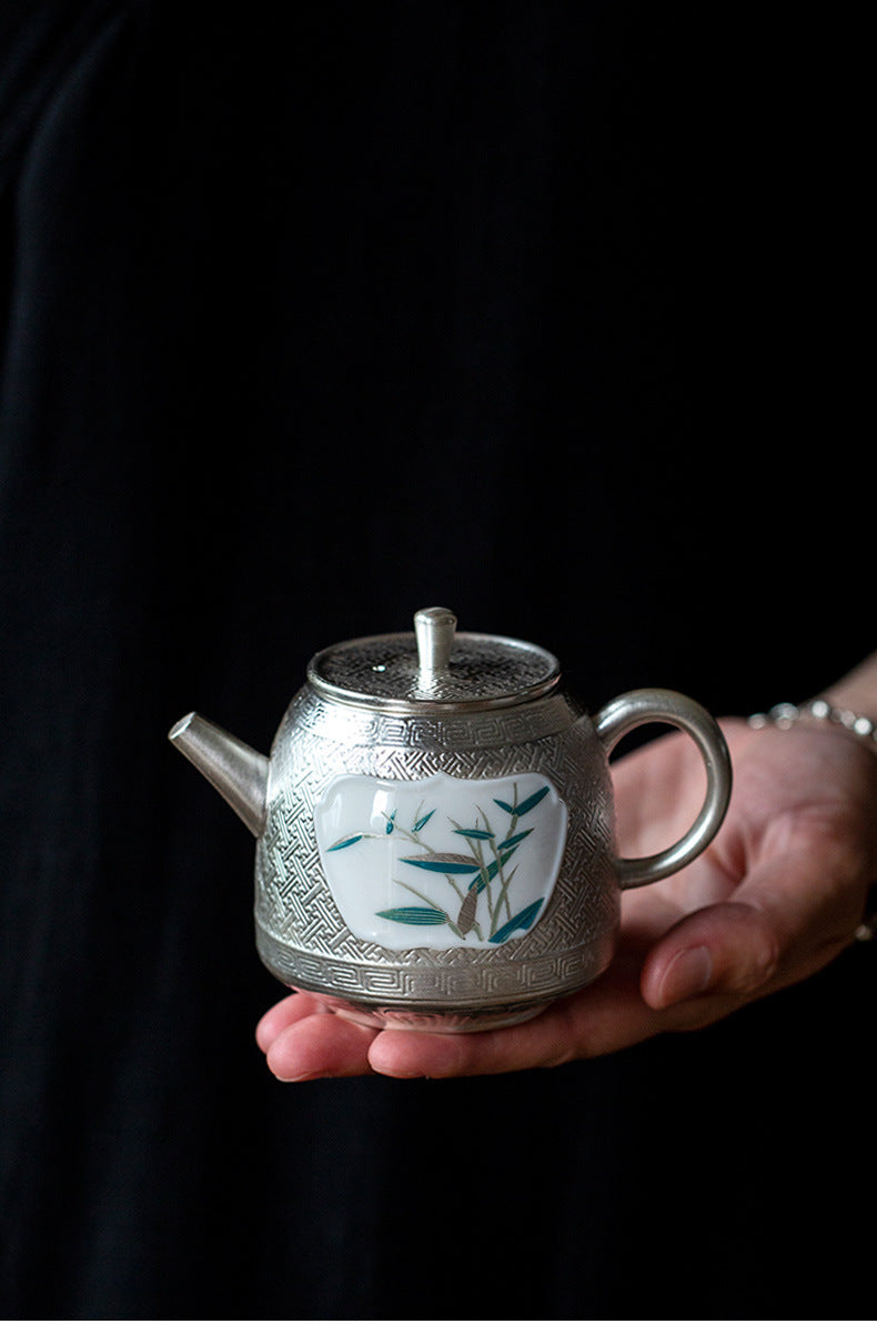 This is a gilted silver ceramic teapot