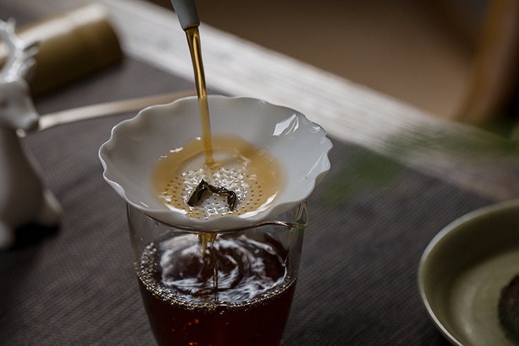 This is a white ceramic tea filter tea funnel